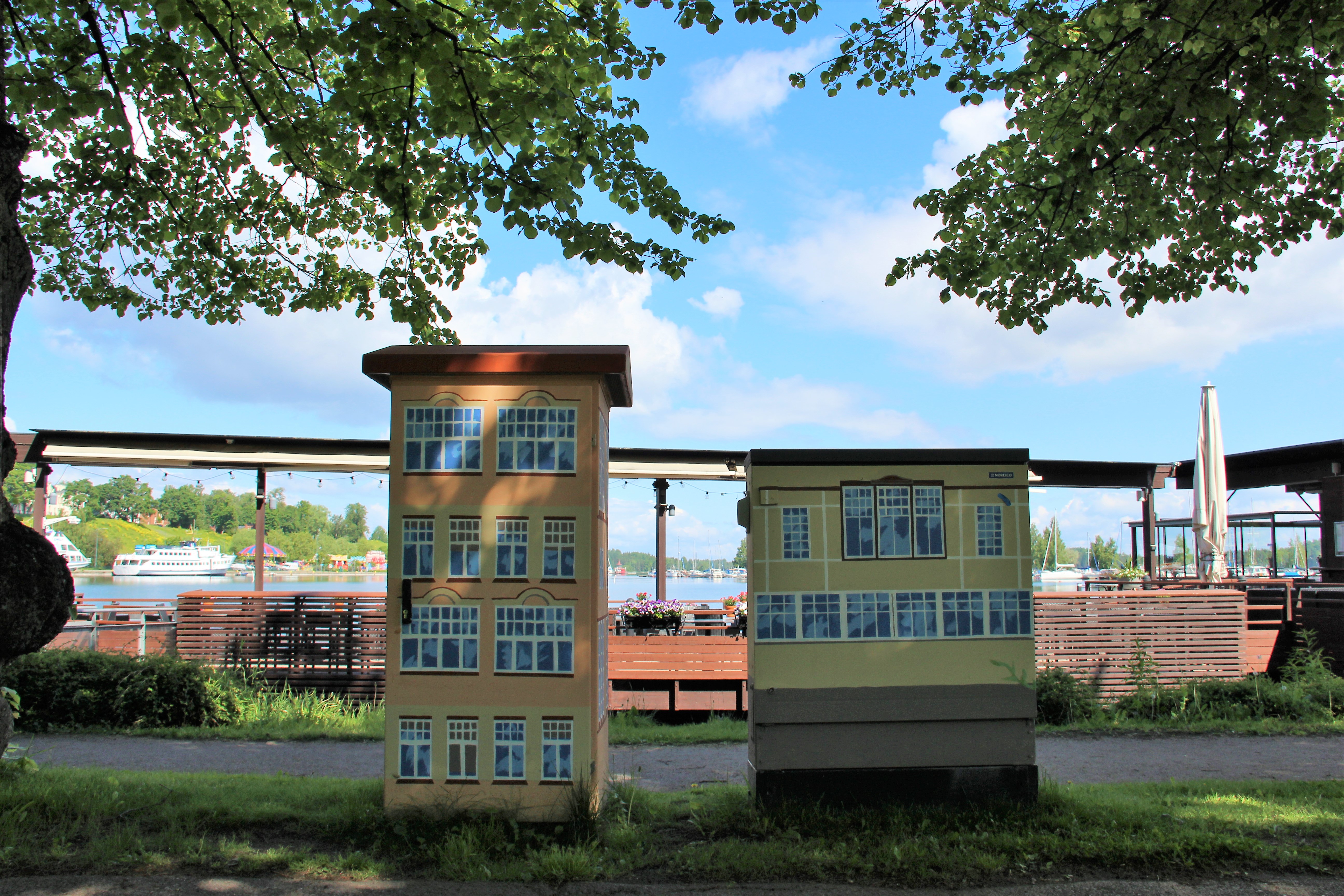 Kaksi rakennuksiksi maalattua sähköjakokaappia Lappeenrannan satamassa.